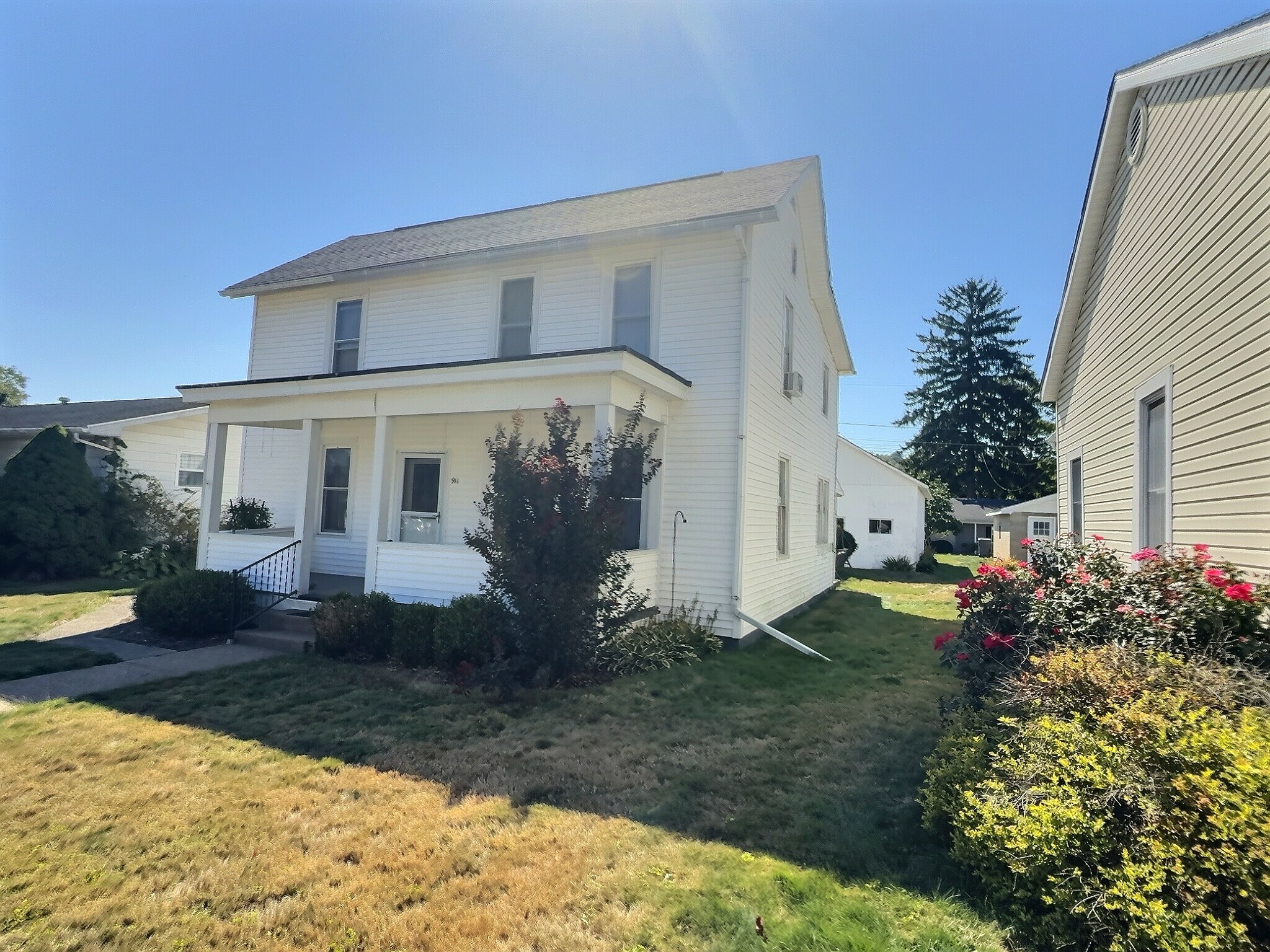 Front angle view with porch and neighboring properties